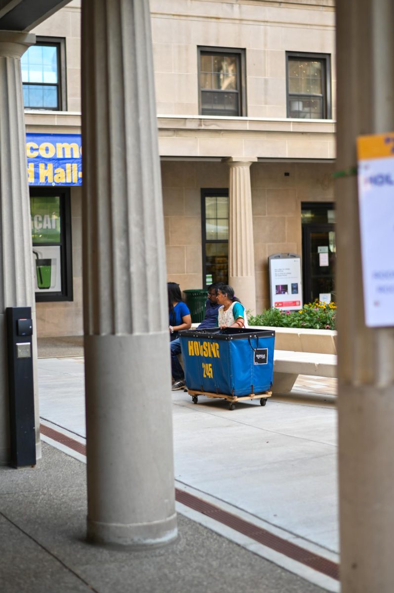 A family sits outside of Holland Hall in the quad with a housing cart on Tuesday afternoon.