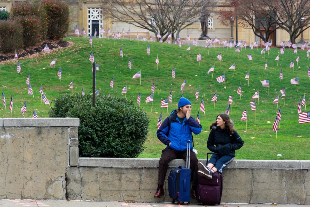Students with suitcases wait for a bus outside Soldiers and Sailors.