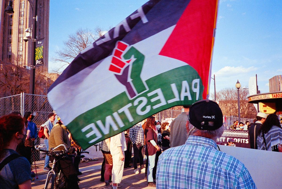 A protester waves a “Free Palestine” flag in Schenley Plaza on Friday, Mar. 14.
